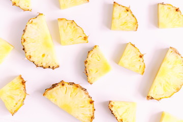 Pattern made of sliced pineapples. Slices of pineapple on a light pastel pink background. Summer concept. Flat lay, top view, copy space 