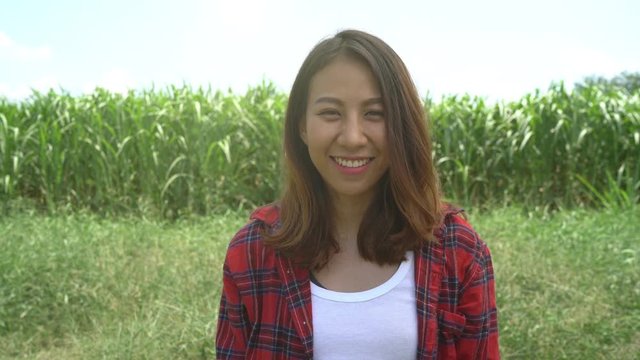 Cheerful asian female farmer and entrepreneur posing in the corn crop and smiling at camera, agriculture and cultivation concept.