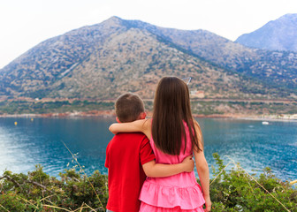 Girl and boy together outdoors. small brother embracing older sister near the sea.