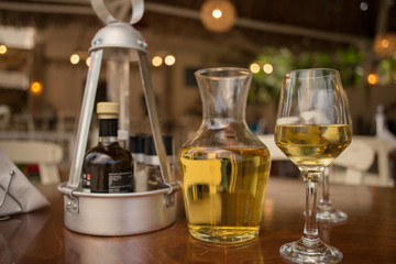 Pouring white wine into the glass against wooden table. Romantic dinner.
