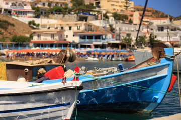 Fototapeta na wymiar small fishing boats at pier in fishing village named Bali with mountains at background in Crete, Greece.