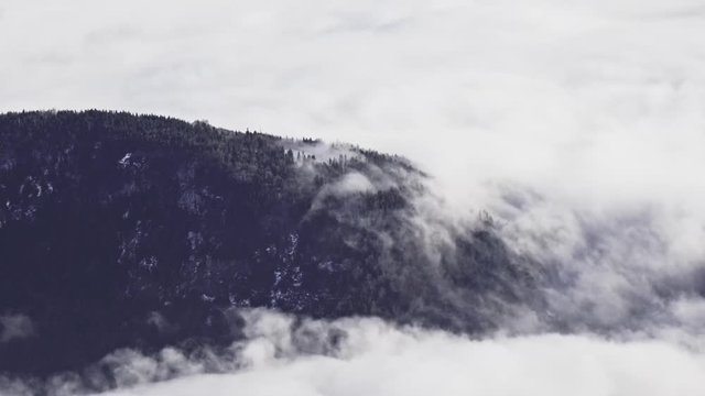 4k close up shot of clouds flowing over a hill.