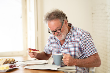 happy old man reading the newspaper while having breakfast