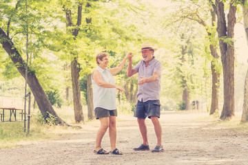 Fototapeta premium Portrait of a beautiful happy senior couple in love dancing in the park