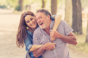 Happy daughter embracing her senior father from back in the park
