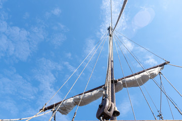 Tigging and masts of an old sailing ship against the blue sky with clouds. Travel adventure and...