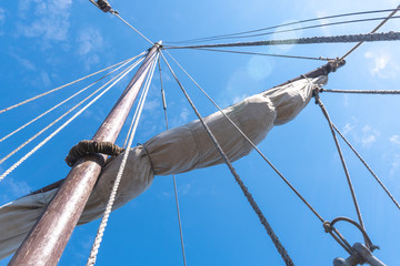 Tigging and masts of an old sailing ship against the blue sky with clouds. Travel adventure and...