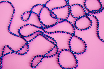 Ornament of blue beads on a pink background.
