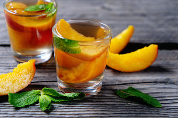 Peach cocktail or tea with mint on wooden background.