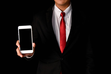 Business concept. Businessman is playing mobile on black background. Business people are browsing the Internet with information technology.