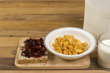 Morning easy breakfast, bread, jam , and cornflakes on wooden background