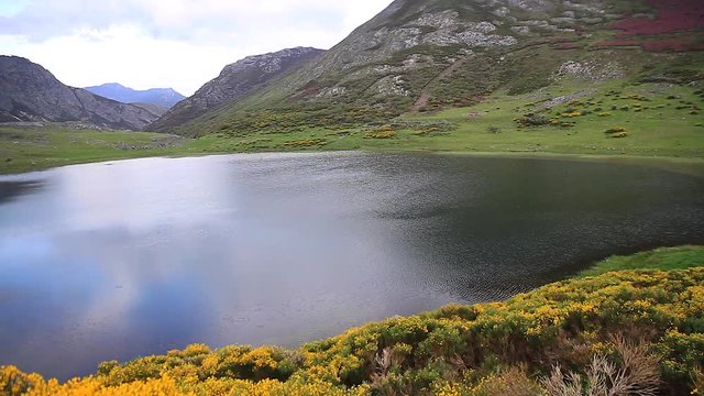 
Panor&aacute;mica de derecha a izquierda de paisaje con lago natural entre monta&ntilde;as , en primavera, con brezos florecidos. Lago de Isoba. Leon
