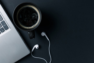 Minimal workspace with Laptop, coffee Cup and headphones copy space on dark background. Top view. Flat lay style.