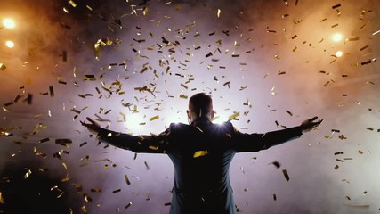 Successful businessman with arms up celebrating his victory. Celebrating success. Low angle view of excited young businessman keeping arms raised and expressing positivity while stands on the stage in
