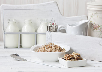 Granola, walnuts and milk healthy breakfast. Close-up, selective focus, shallow depth of field. White vintage background