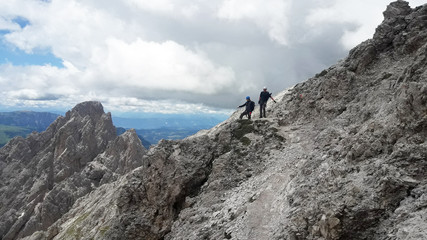 Fototapeta premium climbers on the slope of a rocky mountain, far below the valley, in the sky, fluffy clouds