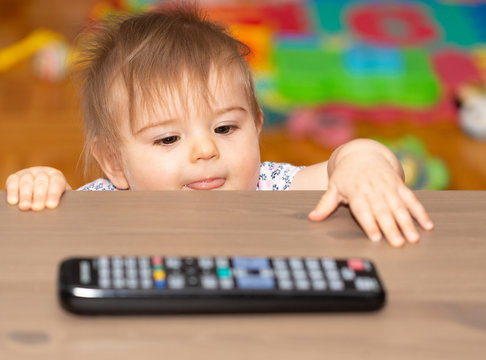 Baby Girl Holding A Remote Control 1