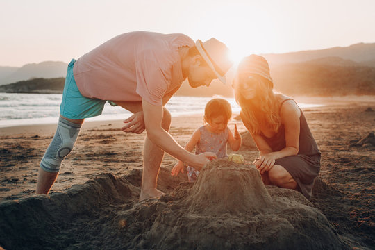 happy family having fun together on the beach at sunset. Building sand castle horizontal view