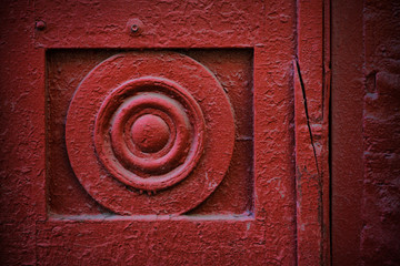 fragment of a red old wooden door with a round element