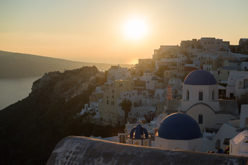 Whitewashed Houses and Church on Cliffs with Sea View and Sunset in Oia, Santorini, Cyclades, Greece