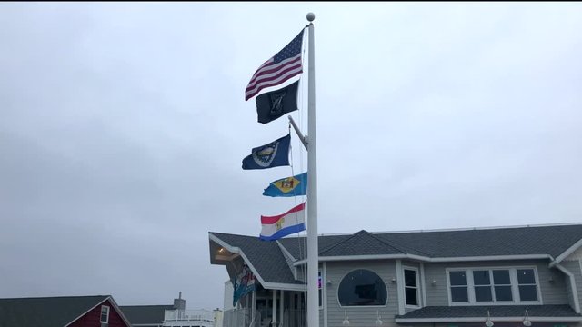 Flags waving on a flag pole with the wind during a storm.