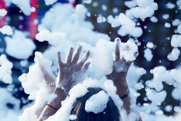 raised hands of a woman in a foam disco