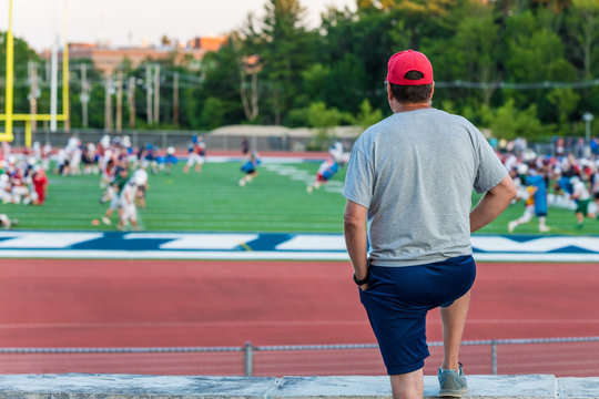 A standing man is watching a football game
