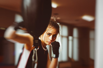 Woman with black boxing wraps on hands boxing in ring. Active girl fight. Right hook with motion blur