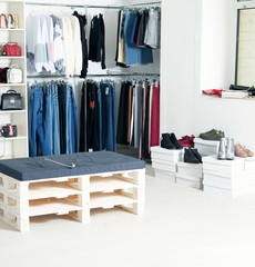 In the clothing store: jeans, jackets, shoes, bags on shelves and hangers. Showcase with new things.