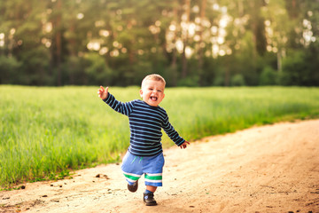 small laughing boy runs along the forest road
