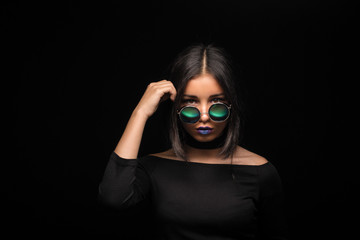 Portrait of cool crazy brunette fashionable girl in sunglasses, casual hairdo on black background. Woman like bitch with pretty makeup big lips