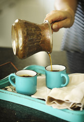 A woman is pouring coffee in a cups