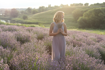 Fototapeta na wymiar attractive woman standing with small bouquet in violet lavender field