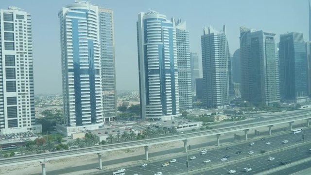 A striking view of a busy ten lane highway with heavy traffic and a row of residential and business skyscrapers in Dubai on a sunny day. 