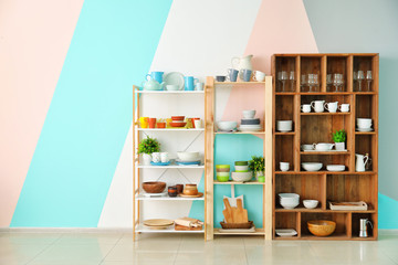 Kitchen shelving with dishes on color wall background