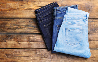 Blue jeans of different shades on wooden background, top view