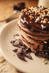 A view of delicious cocoa pancakes with dark chocolate and powdered sugar on a wooden table