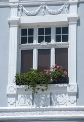 Fototapeta na wymiar Window of old retro blue painted ornamented house facade closeup in sunny day