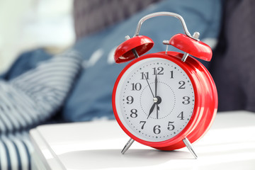 Analog alarm clock on table in bedroom. Time of day