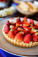 Delicious, mouthwatering and colorful Fresh Summer Strawberry Tart, simple decoration yet elegance with gold leaves. Selective focus.