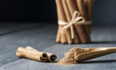 Photo sur Plexiglas Herbes Close up cinnamon sticks and powder healthy spice on black wooden background  