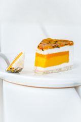 Piece of mango, coconut, passion fruit cake on white wooden table. Minimalism dessert food photography concept, copyspace