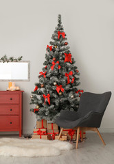Decorated Christmas tree and armchair in stylish living room interior