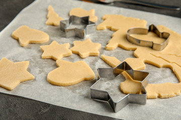 Cutters and raw Christmas cookies on table. Festive treats