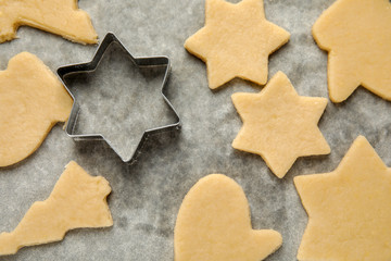 Raw Christmas cookies and cutter on baking parchment, top view