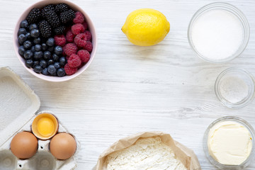 Frame of raw ingredients for cooking berry pie on white wooden background, view from above. Flat lay, overhead. Copy space.