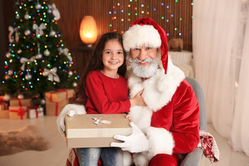 Fototapeta na wymiar Little child with Santa Claus and Christmas gift at home