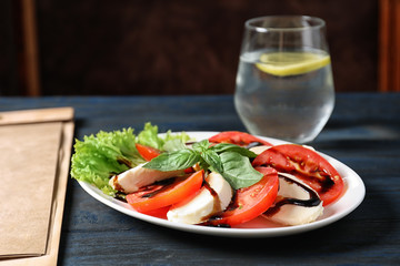 Plate with delicious fresh salad and glass of drink on table