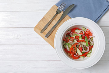 Plate with delicious fresh salad on table, top view