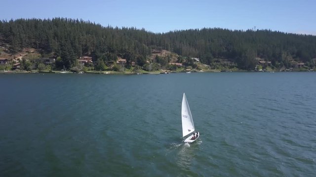 Aerial footage following two kids sailing on a lake UD
